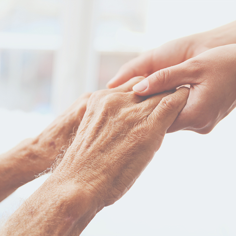 A hospice nurse holdings hands with a patient